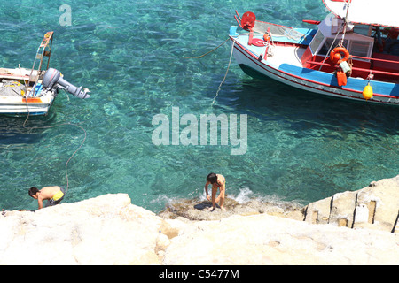 Due ragazzi giocare vicino all'oceano sulle rocce a Creta Foto Stock