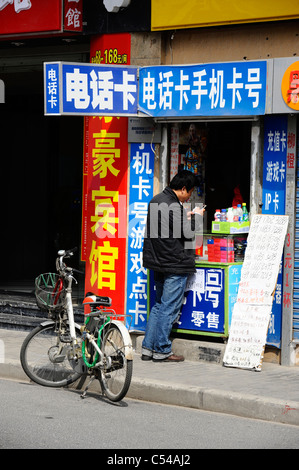Un uomo cinese utilizzando un telefono cellulare nella città vecchia Shanghai Foto Stock