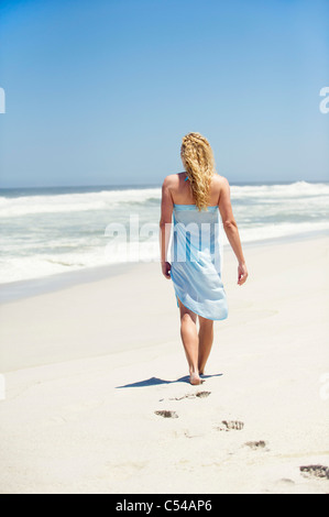 Vista posteriore di una donna di camminare sulla spiaggia Foto Stock