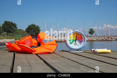 Il sole alto indice UV di lettura su un portatile indice UV meter su un luglio pomeriggio. Consigliata protezione solare a portata di mano come è il giubbotto di salvataggio Foto Stock