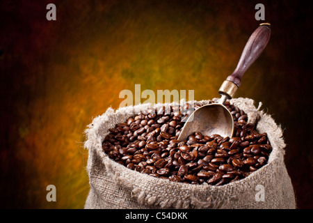 Sacco di chicchi di caffè e scoop. Su uno sfondo scuro. Foto Stock