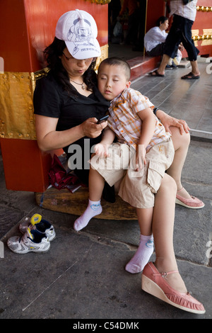 Donna cinese / lady turistico con suo figlio che dorme / boy / stanco bambino. La città proibita a Pechino, Cina. Foto Stock