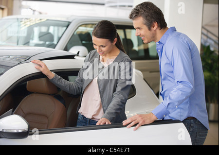 Giovane donna controllo auto dall'interno mentre l'uomo tenendo la porta Foto Stock