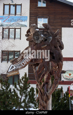 In legno tradizionale volto scolpito con le indicazioni per l'Alpin Express in Saas Fee, Svizzera Foto Stock