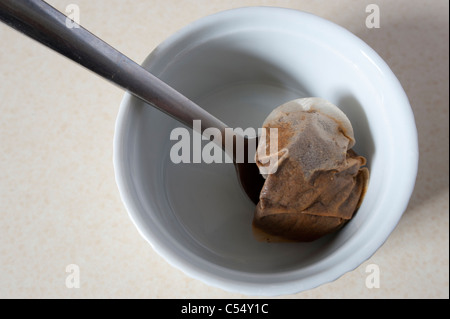 Utilizzate un sacchetto da tè in un piatto bianco con un cucchiaino. Foto Stock