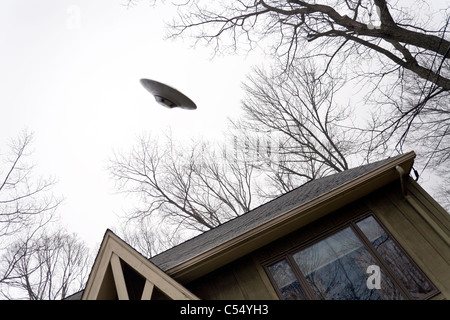 UFO volare al di sopra di una casa. Foto Stock