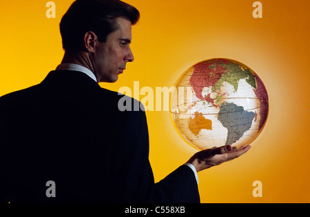 Imprenditore tenendo un globo Foto Stock
