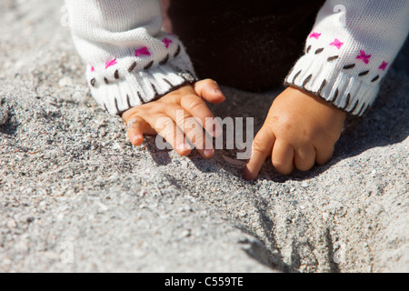 Piccole mani scavando la sabbia sulla spiaggia Foto Stock