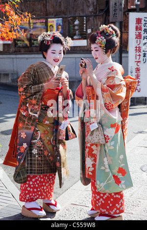 Due donne Geisha vestita in kimono utilizzando i telefoni cellulari, Higashiyama Ward, prefettura di Kyoto, Kinki Regione, Honshu, Giappone Foto Stock