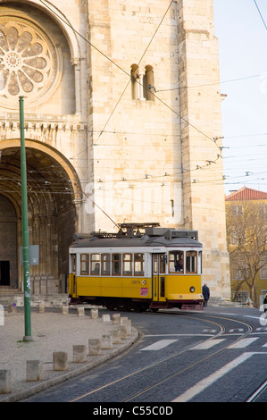 Tram giallo passando da una cattedrale, Se Cathedral, Lisbona, Portogallo Foto Stock