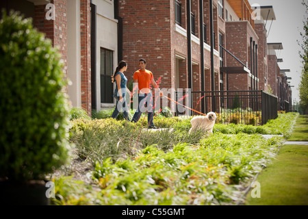 Coppia giovane camminando su un marciapiede con il loro cane Foto Stock