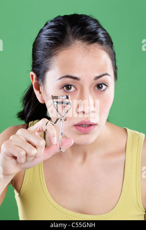 Giovane donna utilizzando un bigodino di ciglia Foto Stock