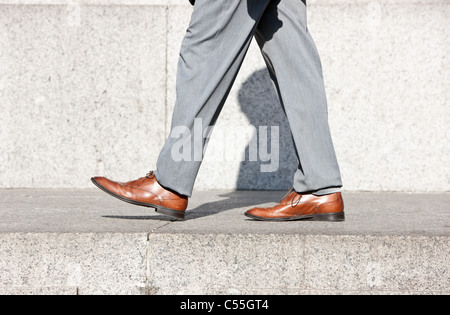 Uomo di gambe con le scarpe marrone passi avanti Foto Stock