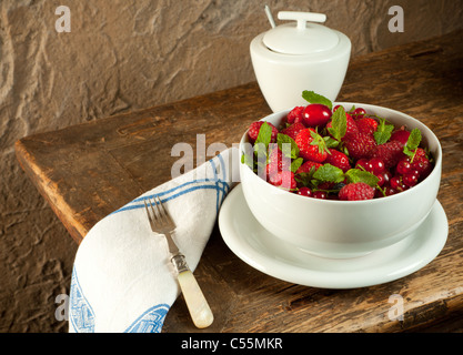 Deliziosi frutti estivi in una ciotola su un antico tavolo in legno Foto Stock