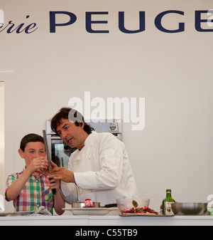 Il francese celebrity chef Jean Christophe Novelli con un ragazzo dal pubblico rendendo caramello spirale durante una dimostrazione culinaria Foto Stock