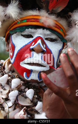 Un Tribeswoman di Papua Nuova Guinea dipinto il suo volto Foto Stock