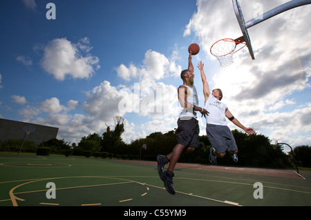 Punteggio maschio all'aperto durante la partita di basket di due su due Foto Stock