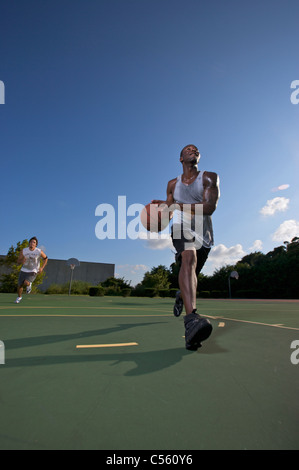 I maschi a giocare all'aperto street basket con una guida al carrello Foto Stock