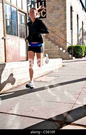 Atleta femminile in esecuzione sul marciapiede, Midtown, San Diego, California, Stati Uniti d'America Foto Stock