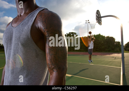Primo piano della muscolare di giocatore di basket con tatuaggio sul outdoor pallacanestro Foto Stock