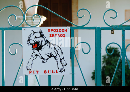 Attenzione del pit bull dog sign in inglese e greco Foto Stock