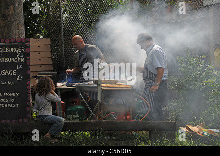 Un sacco di fumo come uomini cucinare al barbecue presso la Comunità Patchfest evento festival a Brighton Regno Unito Foto Stock