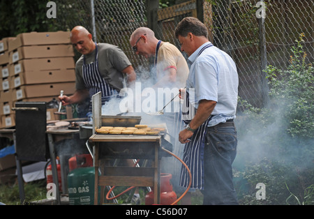 Un sacco di fumo come uomini cucinare al barbecue presso la Comunità Patchfest evento festival a Brighton Regno Unito Foto Stock