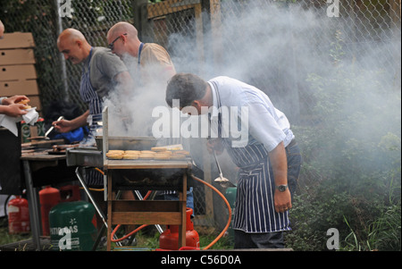 Un sacco di fumo come uomini cucinare al barbecue presso la Comunità Patchfest evento festival a Brighton Regno Unito Foto Stock