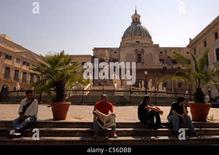 Quattro uomini seduti sui passi presso la Fontana Pretoria e Chiesa di San Caterina in Palermo Foto Stock