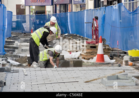 Operai del consiglio scavano la strada sostituendo le pietre di pavimentazione nel distretto. High Street, Bangor, Gwynedd, Galles del Nord, Regno Unito Foto Stock