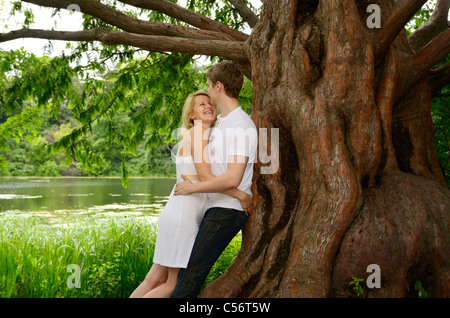 Coppia felice abbracciando sotto una grande Alba albero di sequoia sulla riva di un lago Granatiere Pond High Park Toronto Foto Stock