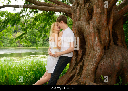 Coppia felice abbracciando e ridere sotto una grande alba albero di sequoia sulla riva di un lago high park toronto Foto Stock