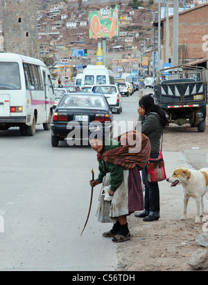 Un molto vecchio e piegate la donna sta tentando di attraversare una strada trafficata in Cusco, Perù Foto Stock