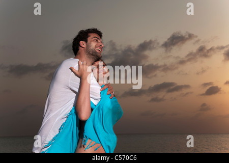 Giovane costeggiata sulla spiaggia al tramonto Foto Stock