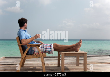 Uomo di bere il caffè sul ponte in spiaggia Foto Stock