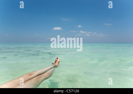 Donna di gambe galleggianti in mare tropicale Foto Stock