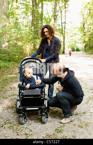 Famiglia spingendo il bambino nel passeggino Foto Stock