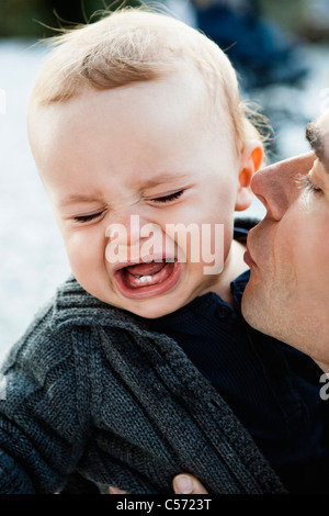 Padre baciare Gridando bambino Foto Stock