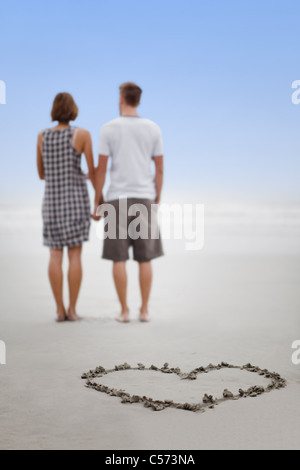 Cuore in sabbia con coppia sulla spiaggia Foto Stock