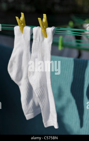 Due Calze sportive bianche e blu asciugamano ancorato su una linea di lavaggio nel sole primaverile Foto Stock
