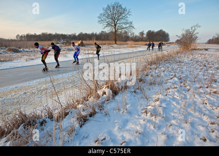 I Paesi Bassi, Blokzijl, inverno, persone il pattinaggio sul lago ghiacciato nel parco nazionale chiamato De Weerribben-Wieden. Foto Stock