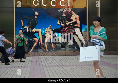 Le donne cinesi a piedi passato un tabellone di gucci di Jinan, capitale della provincia di Shandong, Cina. 07-lug-2011 Foto Stock