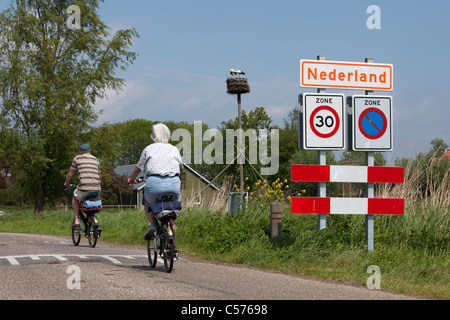 I Paesi Bassi, Nederland, villaggio chiamato Nederland, che significa Paesi Bassi in olandese. Coppia senior in bicicletta. Foto Stock