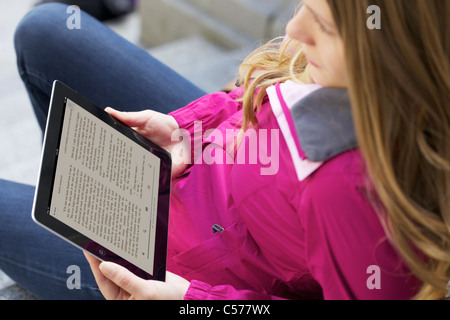 Vista ravvicinata di un Caucasian giovane donna a leggere 'un gioco di troni " libro da Kindle Ipad 2 applicazione Foto Stock