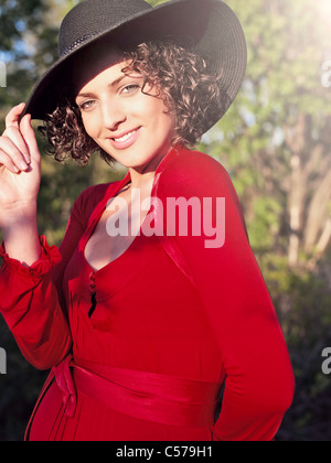 Donna in abito rosso che indossa cappello Foto Stock