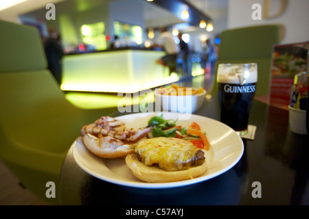 La pancetta e formaggio hamburger servito con insalata e patatine fritte pinta di Guinness in un pub bar ristorante a Dublino in Irlanda Foto Stock