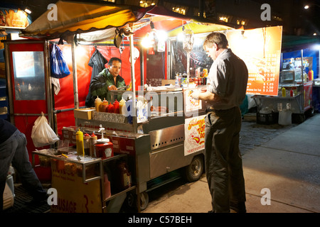 L'uomo acquisto di hot dog di notte da un illuminato fast food in Toronto Ontario Canada America del nord Foto Stock