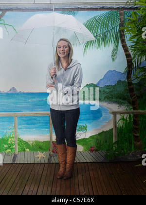 Donna sotto l ombrello con sfondo di spiaggia Foto Stock