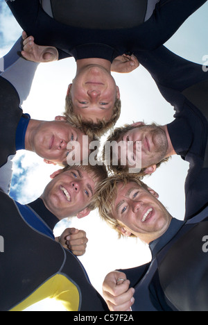 Surfers mettendo teste insieme sulla spiaggia Foto Stock