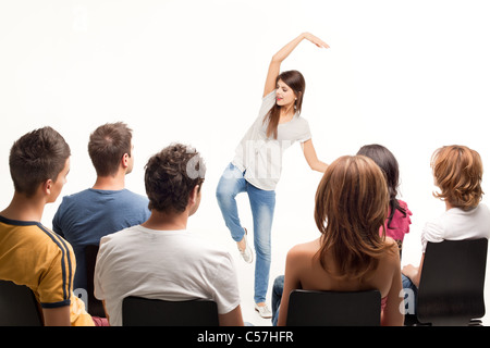 Giovane donna in piedi di fronte alla folla gesti Foto Stock